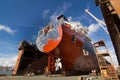 Commercial vessel in dry dock for maintenance. Ship undergoes hull painting and repairs. Maritime, industrial shipping