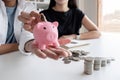 A committed Asian couple saves money together. Counting the coins in the piggy bank