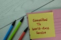 Committed To World-Class Service write on sticky notes isolated on Wooden Table