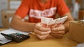 Committed young hispanic teen volunteer enthusiastically counting icelandic krona banknotes for a noble cause at a buzzing charity