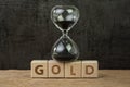 Commodity, gold price countdown, precious metal price, hourglass or sandglass on wooden cube block with alphabet building the word