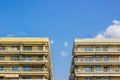 Common apartment building symmetry facade of front side with balcony and windows on clear blue sky background