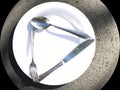 A common, brilliant white dinner plate with eating utensils knife, fork and spoon.