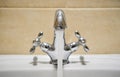 Common mixer tap. Water flowing out of bathroom stainless steel pillar tap into sink. Wasting water by leaving chrome