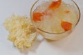 Dessert soup of double boiled snow or white fungus with papaya in glass bowl with dried Tremella fuciformis, on white