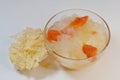 Sweet dish of double boiled snow or white fungus with papaya in glass bowl, with dried Tremella fuciformis, on white