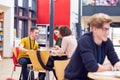 Communal Area Of Busy College Campus With Students Working At Tables