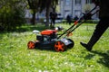 Communal services gardener worker man using lawn mower for grass cutting in city park