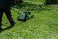 Communal services gardener worker man using lawn mower for grass cutting in city park