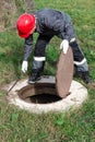 The communal worker opened the sewer hatch and looks inside. Inspection and maintenance of water wells and sewer wells