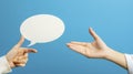 Communication Concept: Hands Offering and Pointing to Blank Speech Bubble on Blue Background Royalty Free Stock Photo