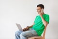 Communication concept. Young arab freelancer guy talking on cellphone, using laptop, sitting over white wall, free space Royalty Free Stock Photo