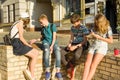 Communication and recreation group of 4 children teenagers. Friends play board game, throwing dice. Background city street Royalty Free Stock Photo