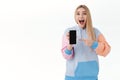 Communication, smartphone and promo concept. Excited happy, attractive blonde girl, cheering smiling broadly and