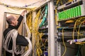 A communication specialist with hand-wound wires works in the server room. A man wrapped in cables is laying new communication lin Royalty Free Stock Photo