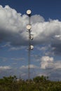 Communication tower surrounded by cloudy blue sky.