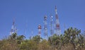 communication towers on top of a mountain in the middle of the desert forest, blue sky in summer day, rocks and palms