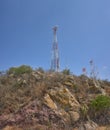 communication towers on top of a mountain in the middle of the desert forest, blue sky in summer day, rocks and palms