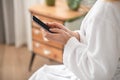 A woman in a white bath robe texting on a smartphone Royalty Free Stock Photo