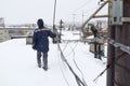 A communications engineer checks the cable during a winter snowfall on the roof of an apartment building