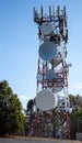 Communications radio tower with satellite dish mobile cell phone against blue sky Royalty Free Stock Photo