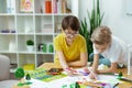 Cheerful dark-haired boy in yellow t-shirt using colorful markers