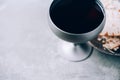 Communion still life. Unleavened bread, chalice of wine, silver kiddush wine cup on grey background. Christian communion concept