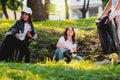 Community project, volunteer mission for gathering rubbish in the park using gloves and garbage bags, one girl making