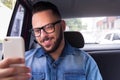 Commuter student man with glasses on smartphone using app texting message in back seat of car. Concept of commute, connection, as