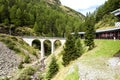 Commuter train is approaching a bridge in the picturesque Swiss Alpes.