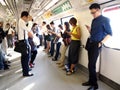 Commuters or passengers inside the MRT pass the time by playing games, watching videos, checking their email or updating their soc Royalty Free Stock Photo