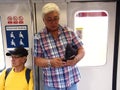 Commuters or passengers inside the MRT pass the time by playing games, watching videos, checking their email or updating their soc Royalty Free Stock Photo