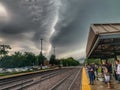 Commuters wait for the train while standing on a Chicago suburbs station platform during a stormy summer morning