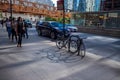 Commuters walk in morning shadows, cars commute on Wacker Dr, and bikes creat shadows on sidewalk