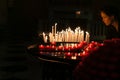 Illuminated face or woman looking at group of prayer candles