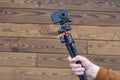 Compact action camera on a flexible tripod in hand on a wooden background Royalty Free Stock Photo