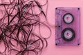 Compact audio cassette on pink background with the tangled tape