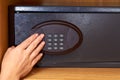 compact black electronic safe with hand in the wooden cupboard in the hotel