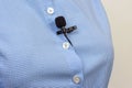 A compact black lav mic is secured on a white buttoned blue shirt, capturing the setup for professional audio recording Royalty Free Stock Photo