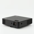A compact, black projector with a rectangular design, featuring a prominent lens on