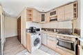Compact and bright kitchen in an older apartment, featuring a built-in washing machine and a coffee machine on the countertop. Royalty Free Stock Photo