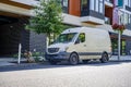 Compact cargo mini van for delivery and small business standing on the urban city street with multi level apartment building