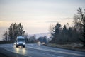 Compact cargo mini van running on turning wet road in twilight with turned on headlight