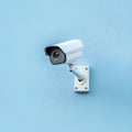 Compact CCTV security camera mounted on light blue background wall Royalty Free Stock Photo