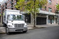 Compact day cab rig semi truck with box trailer making delivery to urban city multilevel apartment neighborhood standing on the Royalty Free Stock Photo