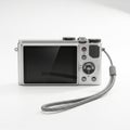 Compact digital camera with wrist strap displaying blank screen on a white surface Royalty Free Stock Photo