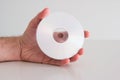 Compact Disc DVD held in hand by Caucasian male hand. Writable side view, close up studio shot, on white