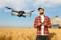 Compact drone hovers in front of farmer with remote controller in his hands. Quadcopter flies near pilot. Agronomist Royalty Free Stock Photo