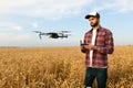 Compact drone hovers in front of farmer with remote controller in his hands. Quadcopter flies near pilot. Agronomist Royalty Free Stock Photo