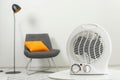 Compact electric fan heater on white table indoors, closeup. Space for text